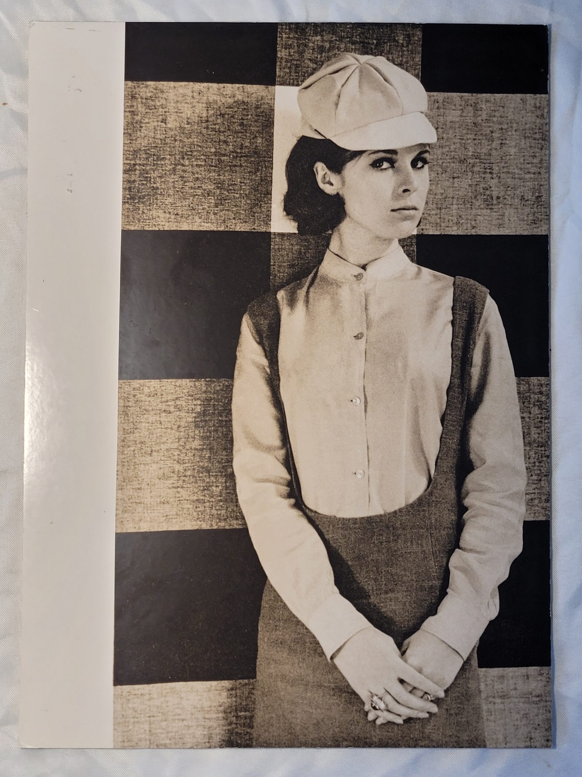 Pretty brunette with hat in front of geometric wallpaper, by Michael Joseph