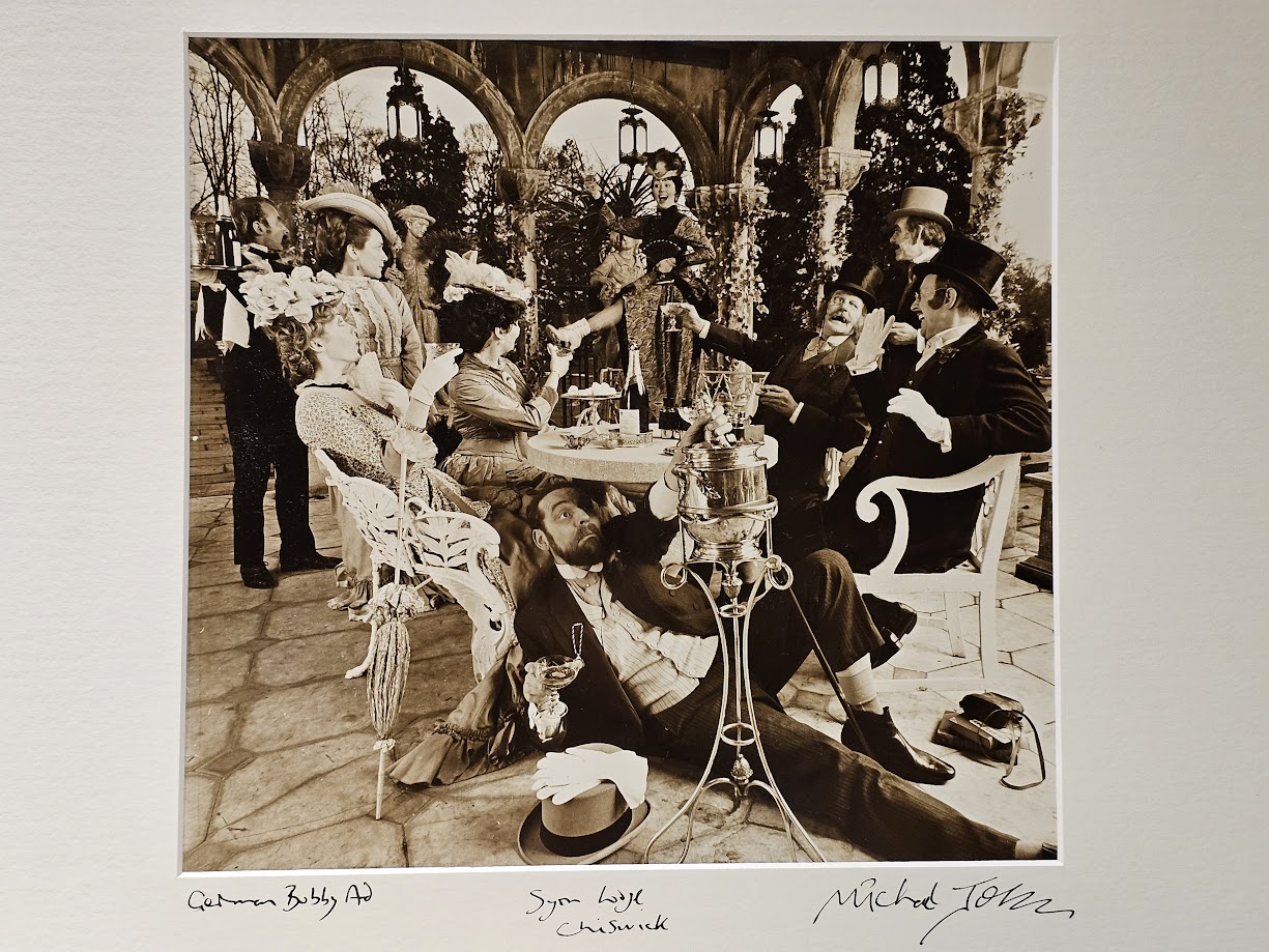 Man drinking under the table, group of people drinking champagne in period costume, advert test print by Michael Joseph
